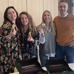 小さなペストリーを持ちながら笑顔で立っている 4 人の同僚たち。