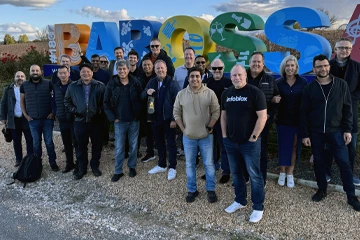 屋外に立っているチーム、一部は Infoblox のシャツを着ていて、会社のイベントで笑顔を見せている。