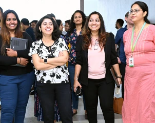 プロフェッショナルなイベントまたはオフィスの集まりで、笑顔で会話する人々のグループ。